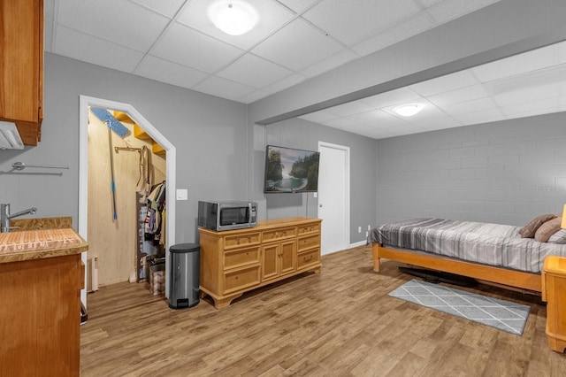 bedroom with a closet, light wood-type flooring, and a drop ceiling