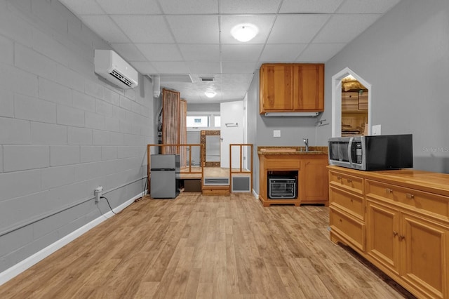 kitchen with light hardwood / wood-style floors, a wall mounted AC, and a paneled ceiling