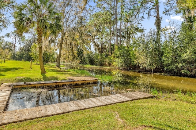 view of dock with a lawn and a water view