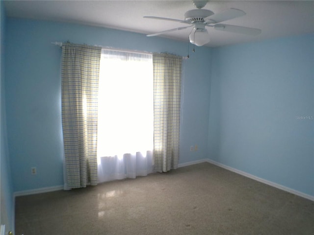 carpeted spare room with ceiling fan and plenty of natural light