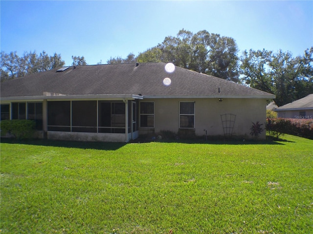 rear view of house featuring a yard and a sunroom