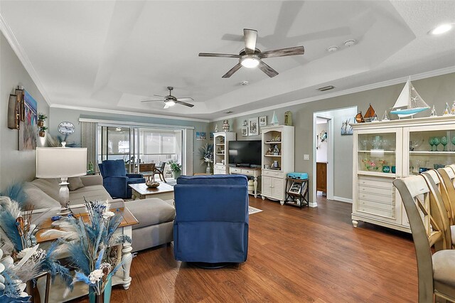 living room with dark hardwood / wood-style flooring, ornamental molding, ceiling fan, and a raised ceiling