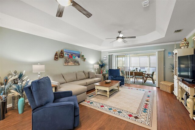 living room with ceiling fan, crown molding, a tray ceiling, and dark hardwood / wood-style floors