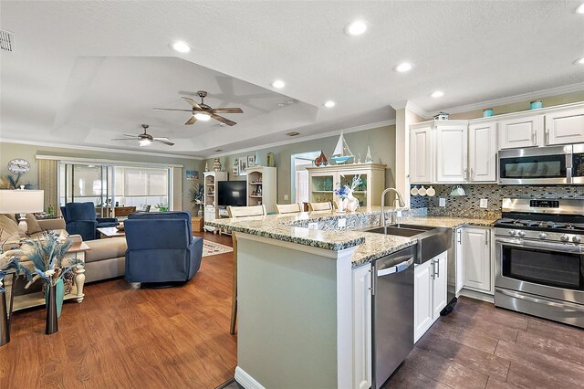 kitchen featuring sink, kitchen peninsula, stainless steel appliances, white cabinets, and dark wood-type flooring