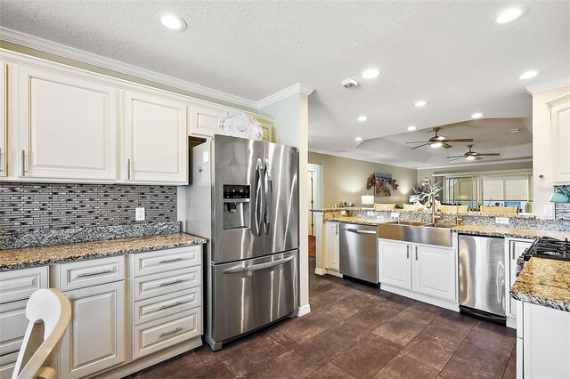 kitchen with light stone countertops, crown molding, appliances with stainless steel finishes, and white cabinetry