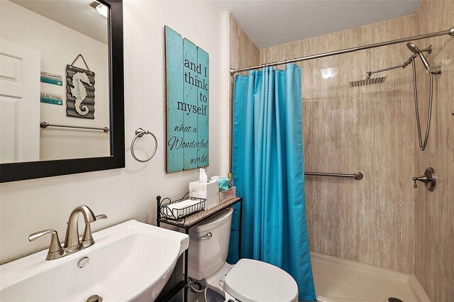 bathroom with sink, a textured ceiling, a shower with curtain, and toilet