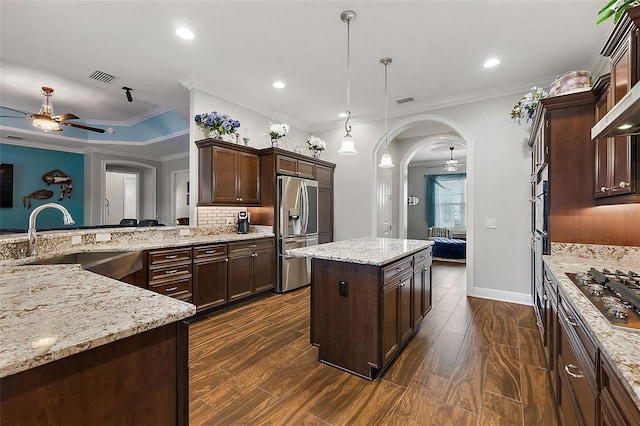 kitchen with a kitchen island, dark wood-type flooring, stainless steel appliances, sink, and pendant lighting