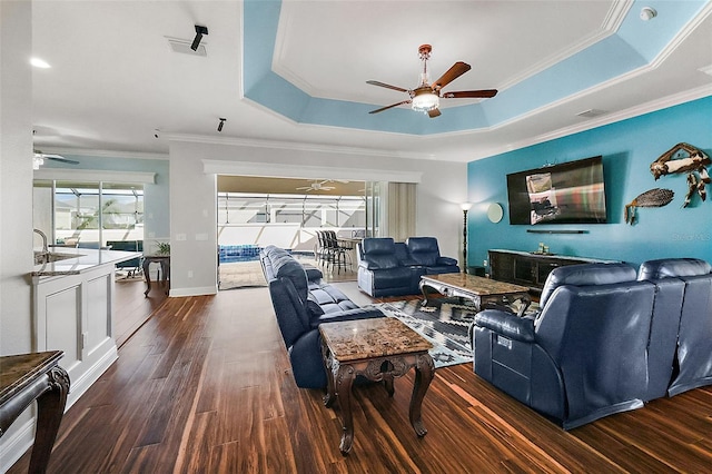 living room with ornamental molding, dark hardwood / wood-style floors, and a tray ceiling