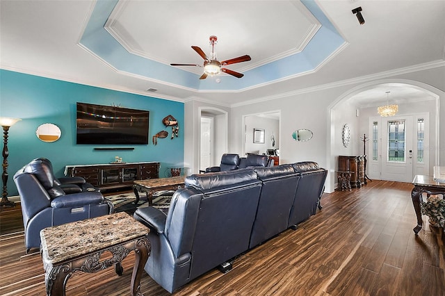 living room featuring ornamental molding, a tray ceiling, dark wood-type flooring, and ceiling fan with notable chandelier