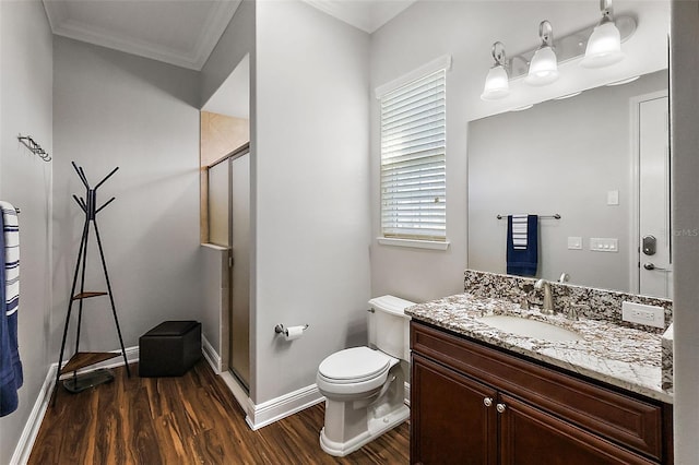 bathroom featuring toilet, a shower with shower door, ornamental molding, hardwood / wood-style floors, and vanity