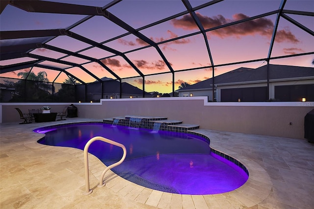 pool at dusk featuring a hot tub, a patio area, a lanai, and pool water feature