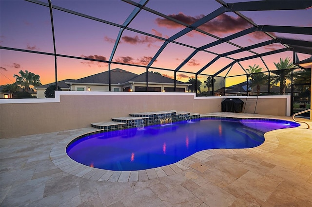 pool at dusk featuring pool water feature, area for grilling, a patio area, and glass enclosure