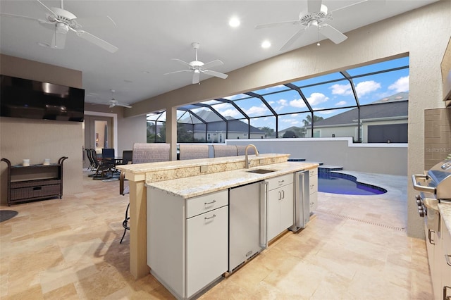 kitchen featuring sink, stainless steel fridge, white cabinets, a breakfast bar area, and a center island with sink