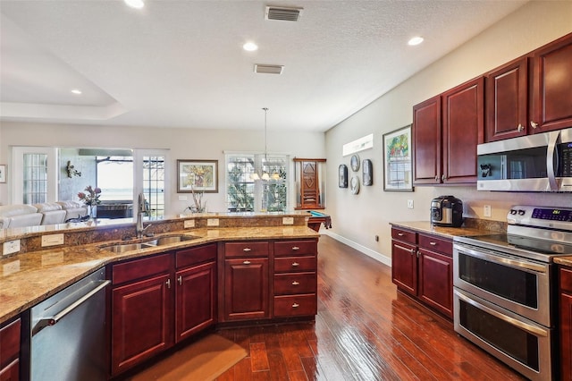 kitchen featuring appliances with stainless steel finishes, sink, a textured ceiling, decorative light fixtures, and dark hardwood / wood-style floors