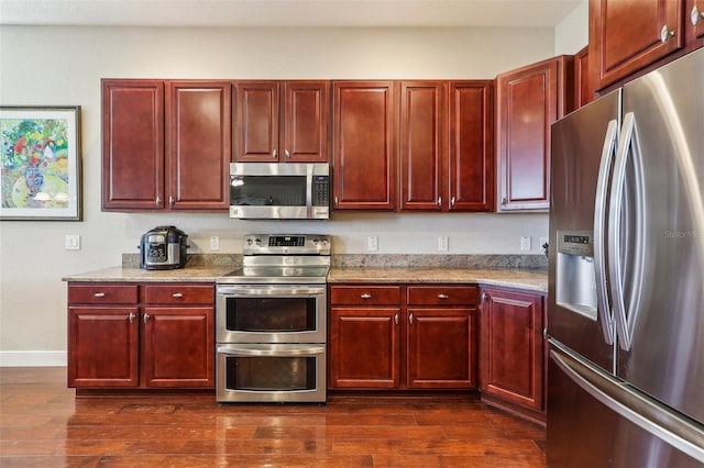 kitchen with light stone countertops, stainless steel appliances, and dark hardwood / wood-style floors