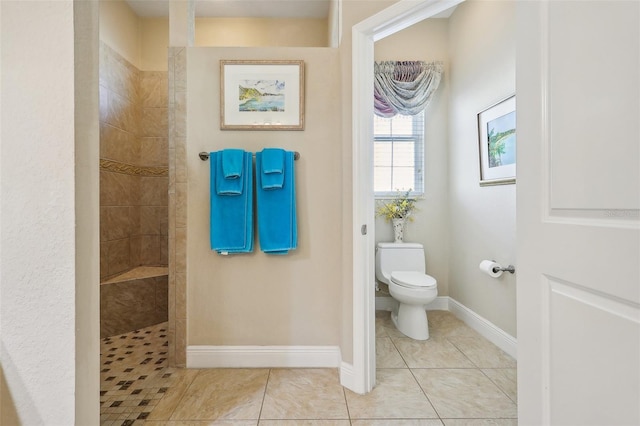 bathroom with a tile shower, toilet, and tile patterned flooring