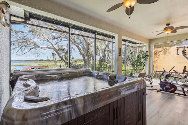 sunroom / solarium featuring a jacuzzi, a water view, and ceiling fan