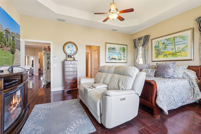 bedroom featuring a raised ceiling, ceiling fan, and dark hardwood / wood-style flooring