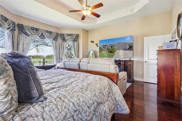 bedroom with a raised ceiling, dark hardwood / wood-style floors, and ceiling fan