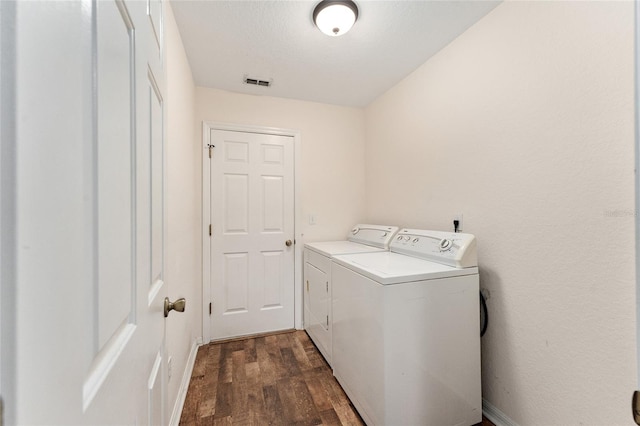 clothes washing area featuring a textured ceiling, washing machine and dryer, and dark wood-type flooring