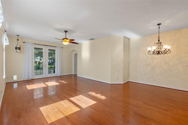 empty room featuring french doors, wood-type flooring, and ceiling fan with notable chandelier