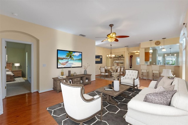 living room featuring hardwood / wood-style floors and ceiling fan with notable chandelier