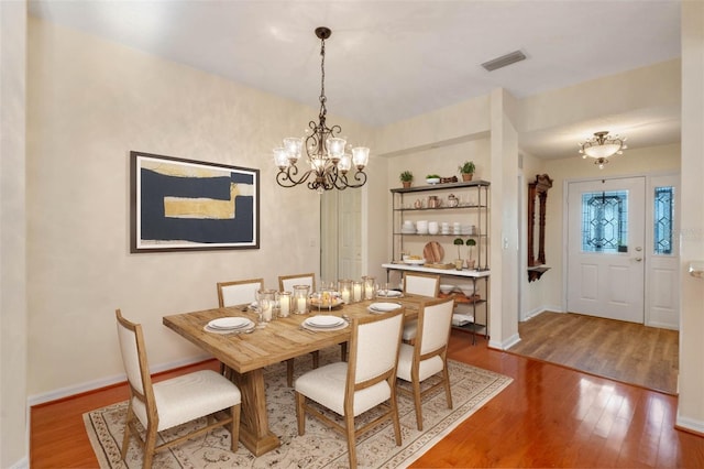 dining space featuring hardwood / wood-style floors and an inviting chandelier