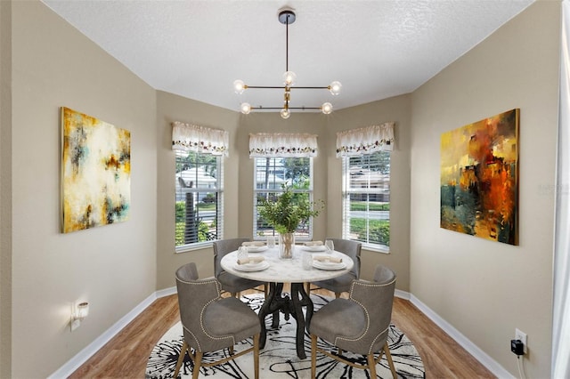 dining area featuring an inviting chandelier, a textured ceiling, and light hardwood / wood-style floors