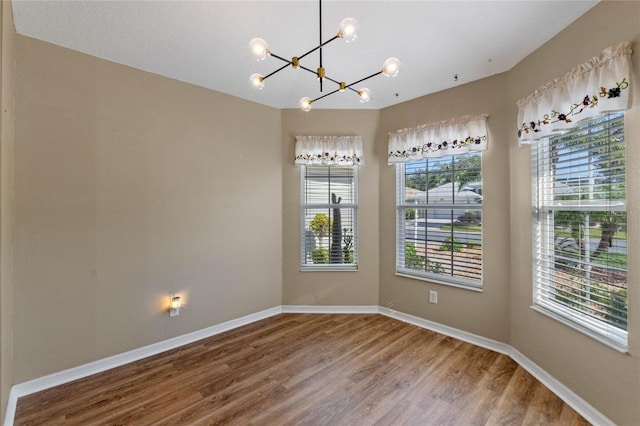 empty room featuring hardwood / wood-style floors and a chandelier