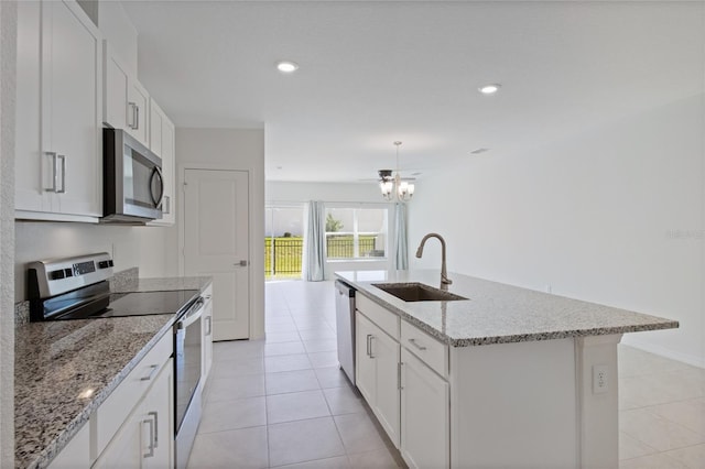 kitchen with a sink, an island with sink, light tile patterned flooring, stainless steel appliances, and white cabinetry