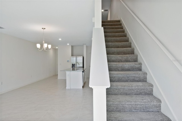 stairway with a notable chandelier, sink, and tile patterned flooring