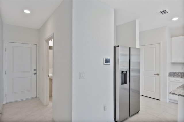 hallway featuring baseboards, visible vents, recessed lighting, and light tile patterned floors
