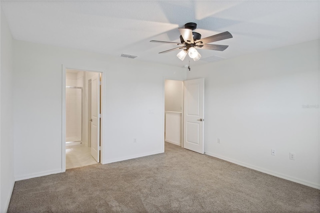 unfurnished bedroom with baseboards, visible vents, light colored carpet, a ceiling fan, and ensuite bath