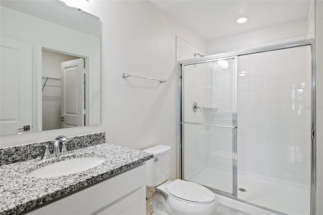 full bathroom with a shower stall, toilet, a walk in closet, and vanity