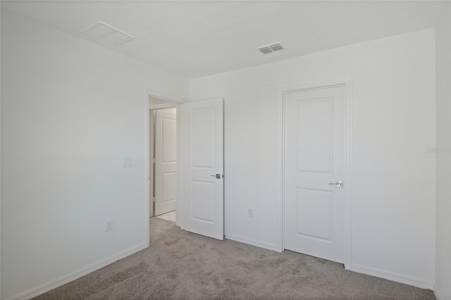 unfurnished bedroom with baseboards, visible vents, and carpet