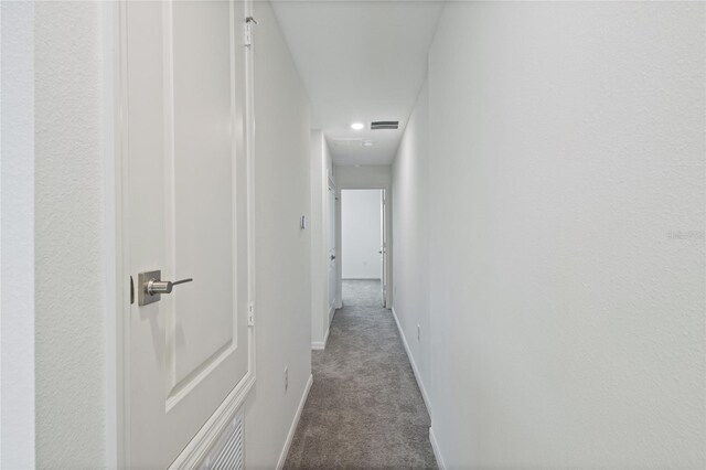 hall with visible vents, carpet flooring, and baseboards