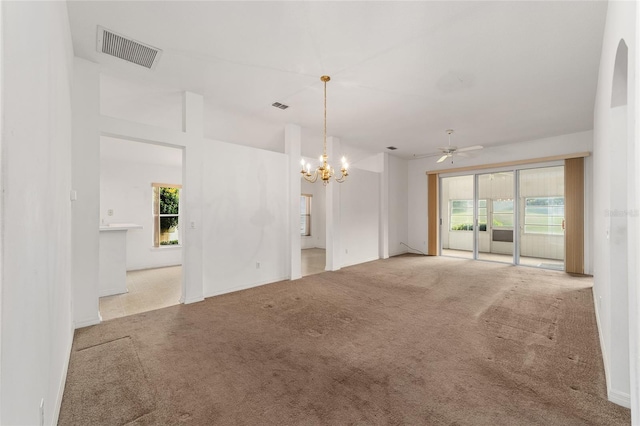 carpeted empty room featuring plenty of natural light and ceiling fan with notable chandelier