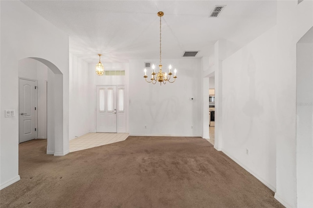 unfurnished room featuring a notable chandelier and carpet floors