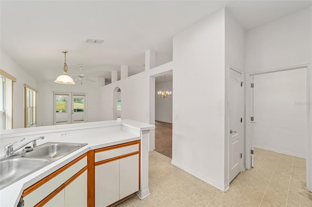 kitchen featuring lofted ceiling, white cabinets, hanging light fixtures, ceiling fan with notable chandelier, and sink