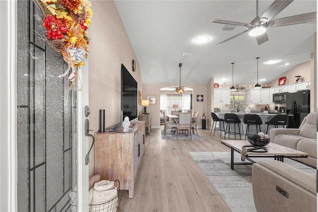 living room featuring lofted ceiling, light wood-type flooring, and ceiling fan