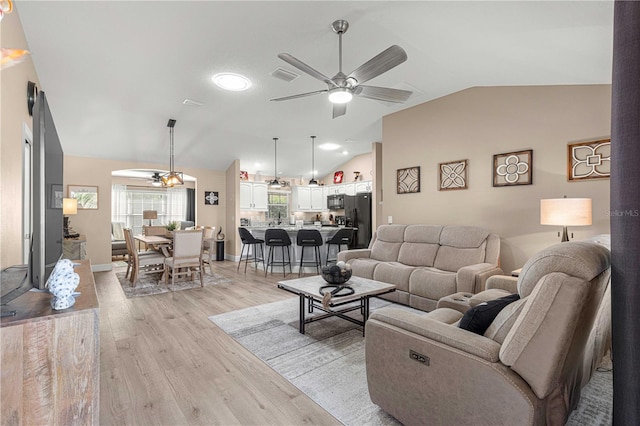 living room featuring lofted ceiling, light hardwood / wood-style flooring, and ceiling fan