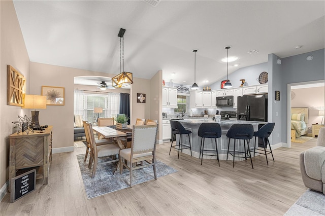 dining space featuring ceiling fan, lofted ceiling, and light wood-type flooring