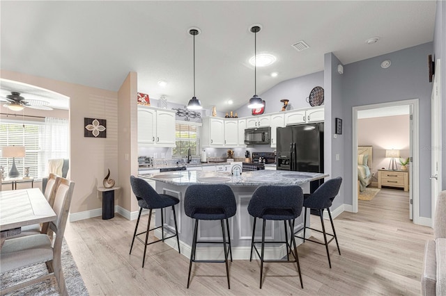 kitchen with black appliances, a center island, ceiling fan, vaulted ceiling, and white cabinets