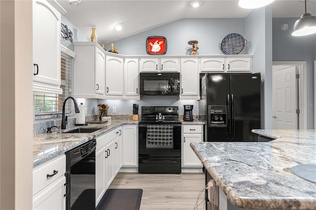 kitchen featuring lofted ceiling, hanging light fixtures, black appliances, sink, and white cabinetry