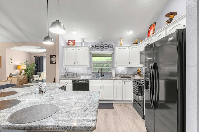 kitchen featuring white cabinets, hanging light fixtures, light wood-type flooring, black appliances, and sink