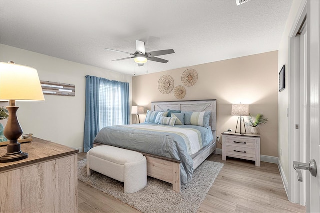 bedroom featuring a textured ceiling, light hardwood / wood-style floors, and ceiling fan