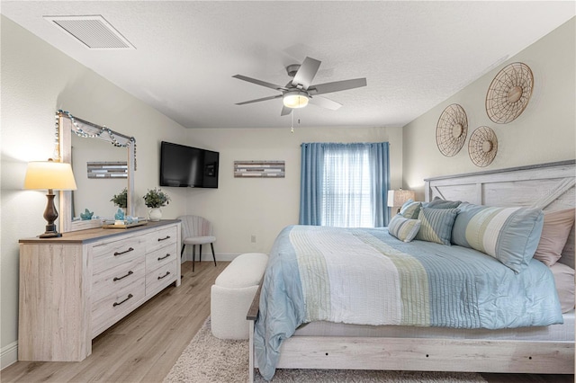 bedroom featuring ceiling fan, a textured ceiling, and light wood-type flooring