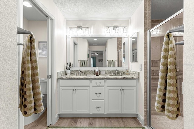 bathroom featuring vanity, a textured ceiling, hardwood / wood-style flooring, and walk in shower