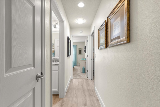 hallway featuring light hardwood / wood-style flooring and a textured ceiling