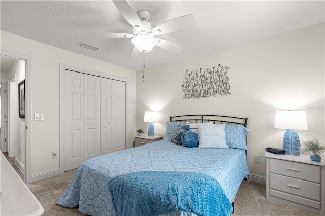 carpeted bedroom with a textured ceiling, a closet, and ceiling fan